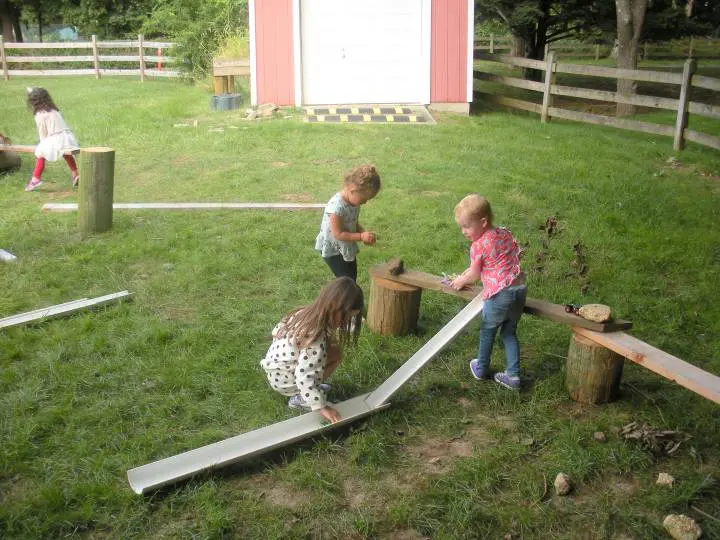Two children playing with a ramp in the grass.