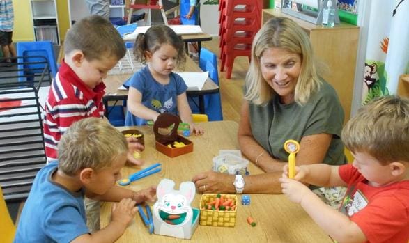 A woman and some children are playing with toys.